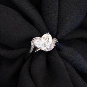 Tina solitaire with heart cut diamond and diamond side stones on a black background.